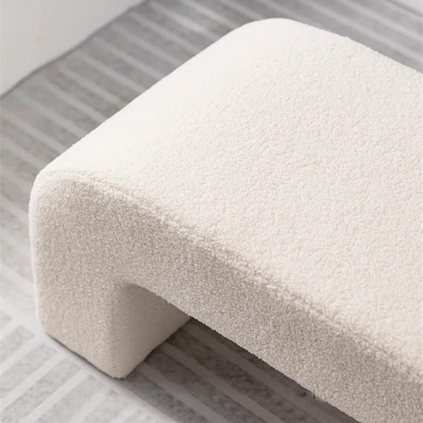 Banc en laine d’agneau positionné au pied du lit, ajoutant une touche de douceur et d’élégance à la décoration de la chambre.