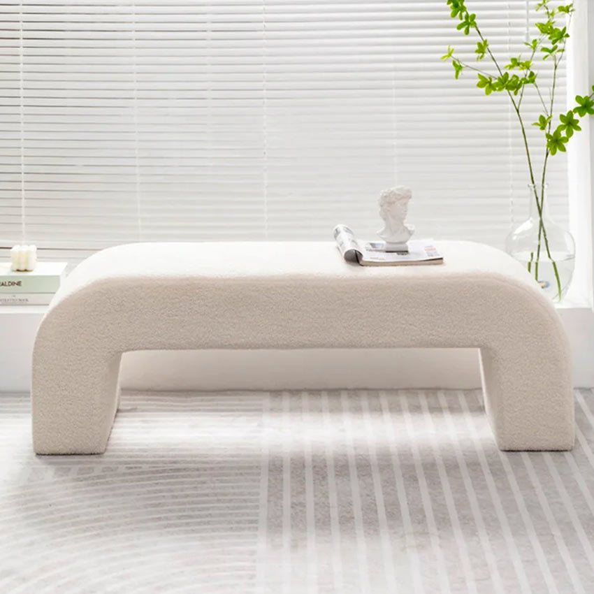 Tabouret design en laine d’agneau placé dans une entrée moderne, parfait pour enfiler ses chaussures avec confort.