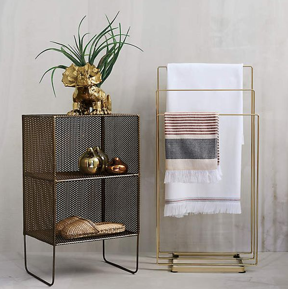 Table d'appoint décorative avec éléphant doré et plante, à côté d'un porte-serviettes avec serviettes.