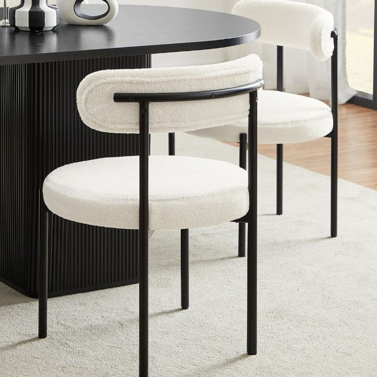 Chaise en bouclette crème autour d’une table en bois clair dans une salle à manger moderne et lumineuse.