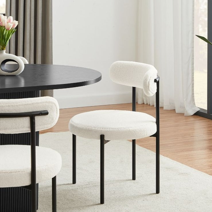 Chaise en bouclette gris clair avec pieds en métal noir, design arrondi et moderne pour salle à manger contemporaine.