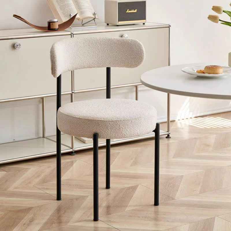 Chaise moderne aux pieds noirs dans une pièce avec une table et des objets décoratifs.