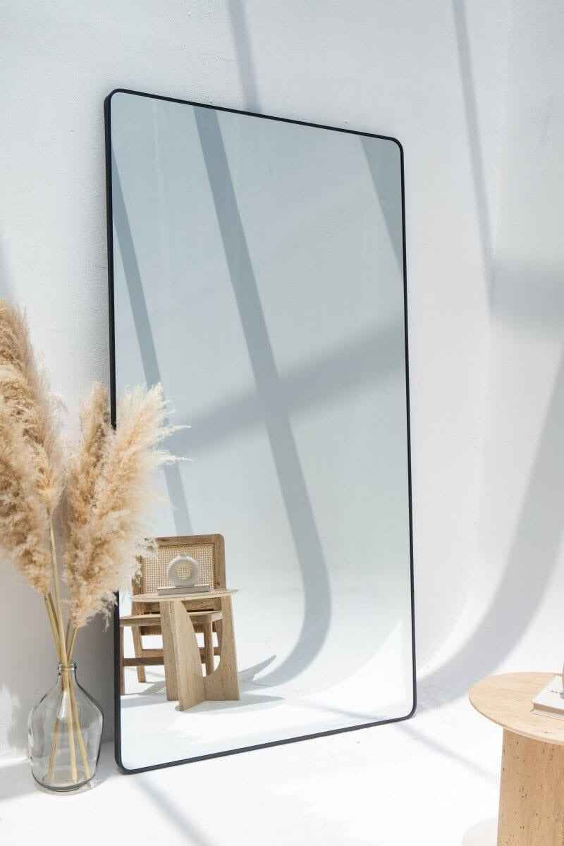 Miroir Adeline noir posé au sol – design épuré et reflet lumineux pour chambre moderne.