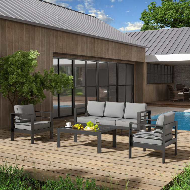 Ensemble d’extérieur 4 pièces disposé sur une terrasse en bois, entouré de plantes vertes et baigné de lumière naturelle.