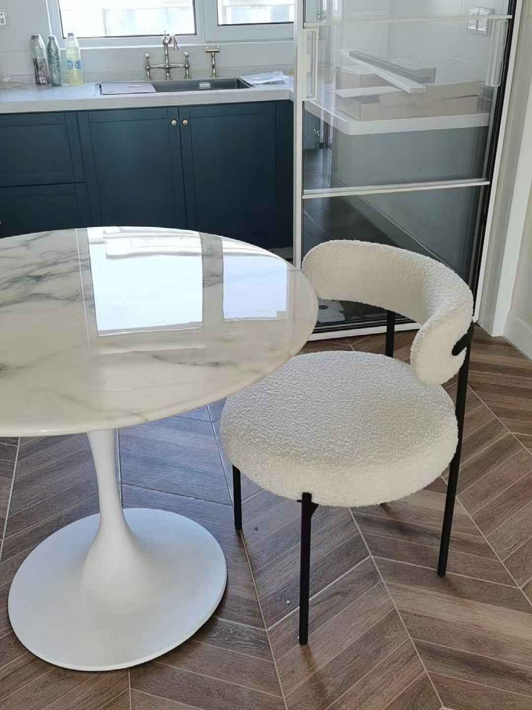 Cuisine moderne avec une table en marbre et des chaises blanches.